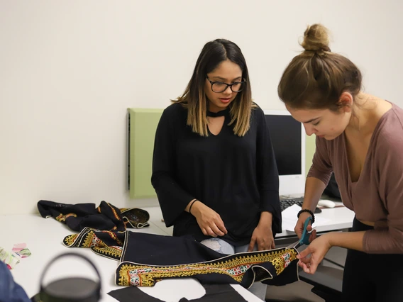 Two women modifying a garment together