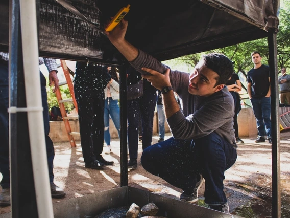 A man using a tool to inspect a structure he's kneeling under