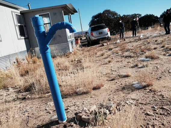 A blue water spout in front of a house on Navajo land.