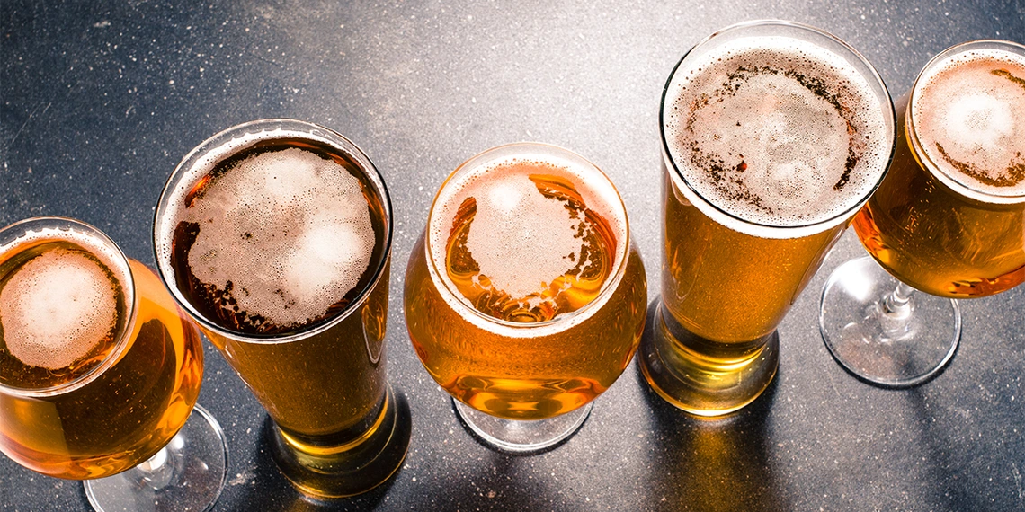 A row of differing beer glasses and beer types