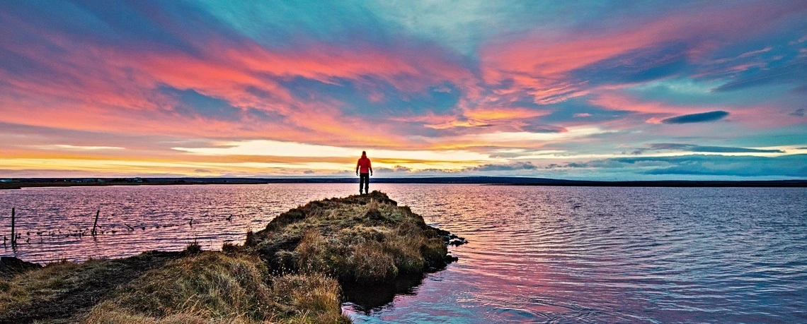 Person overlooking a lake at sunset