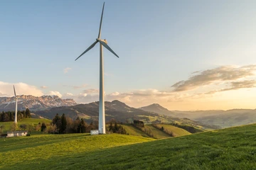 A windmill backdropped by a mountain landscape