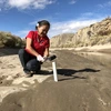 Karletta Chief using a tool to conduct hydrological fieldwork in a riverbed