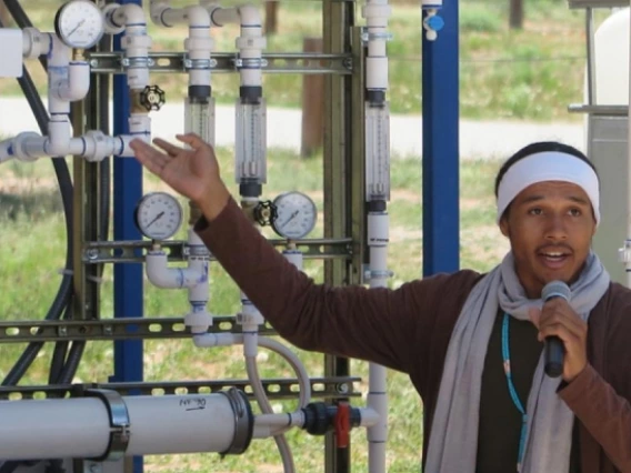 Student giving a talk in front of a water filtration system
