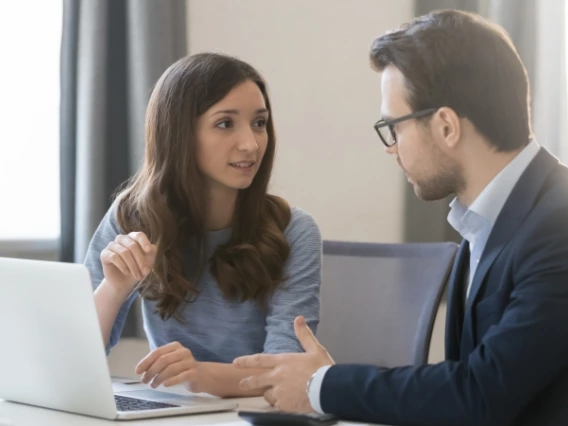 Two economics professionals discussing work next to a laptop