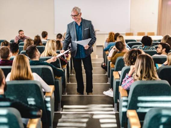 An instructor handing out sheets to students in a lecture hall