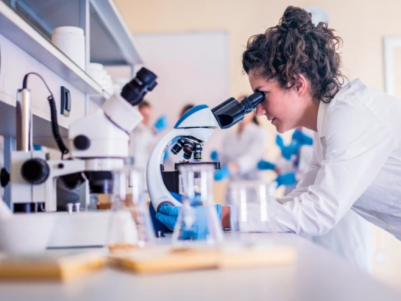 woman looking at a lab sample through a microscope