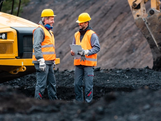 Worker with a clipboard discussing things with another worker in quarry