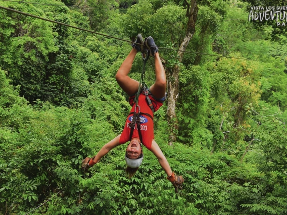 Samantha Araya upside down on a zip line in the tree canopy