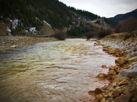 Flowing river with rusty banks in the fall.