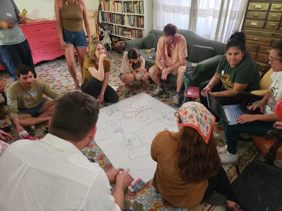 A group of people sit on the ground surrounding a map of North America.