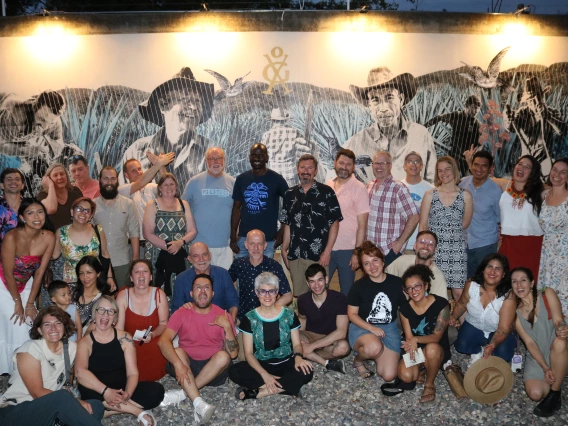 The EMIGRA team posing in front of wall mural at night.