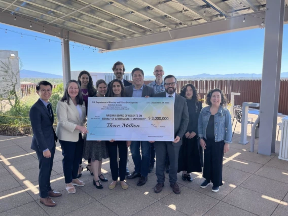 A group of people pose on the ENR2 rooftop with a large check.