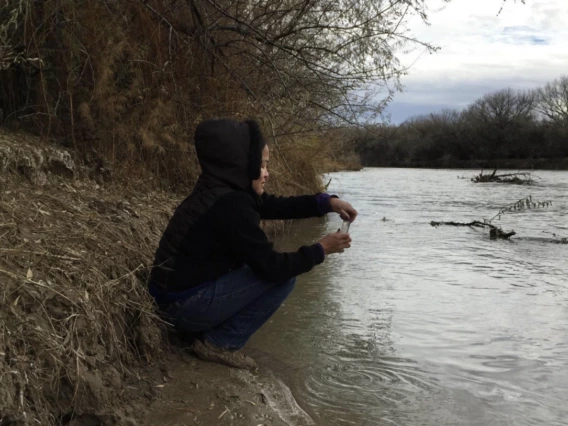 Person sitting along a riverbank