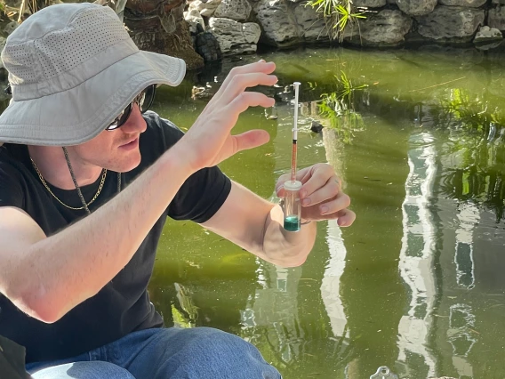 Jack holding up a water sample outside