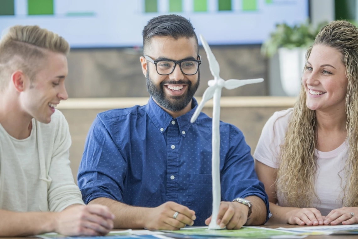 Three students happily examining a wind turbine model