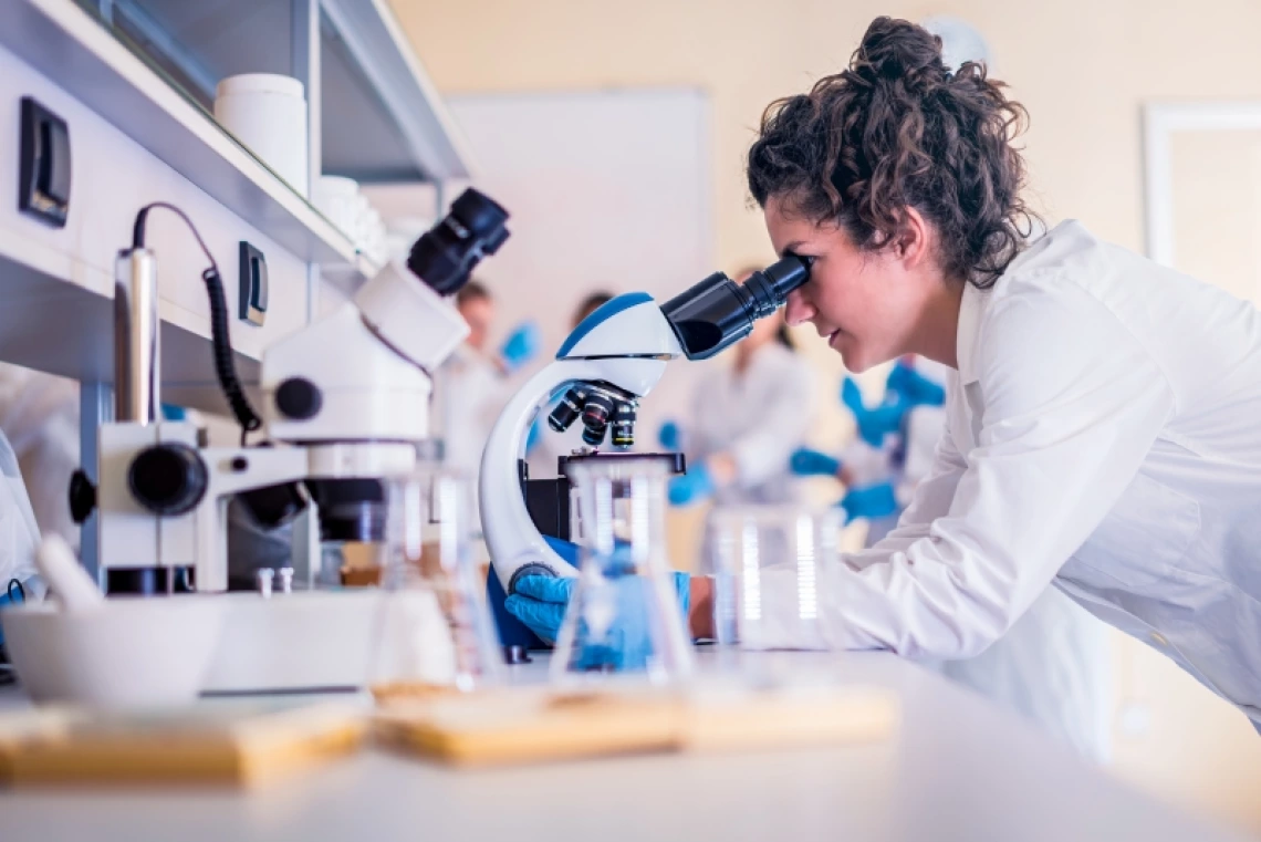 woman looking at a lab sample through a microscope