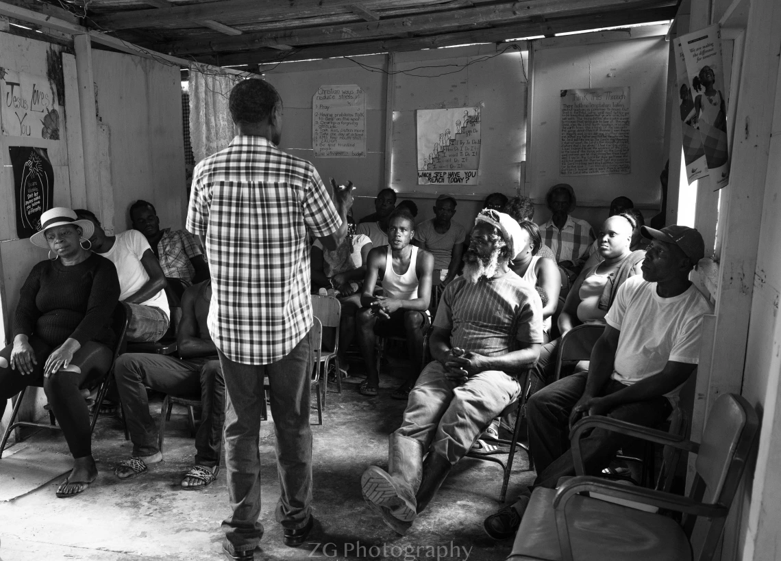 Man stands in front of Jamaican farmers. Black and white photo.