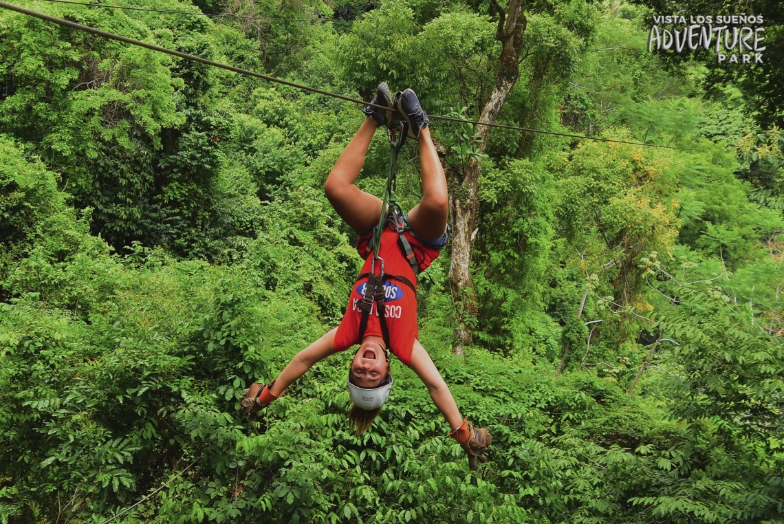 Samantha Araya upside down on a zip line in the tree canopy