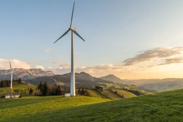 A windmill backdropped by a mountain landscape