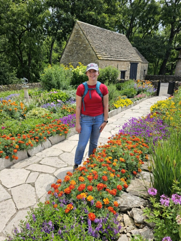 Grace Adams stands in yard with blooming flowers.