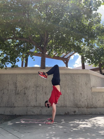 Roger doing a hand stand outside with a jump rope.