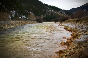 Flowing river with rusty banks in the fall.