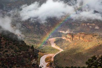 Rainbow and clouds over canyon river